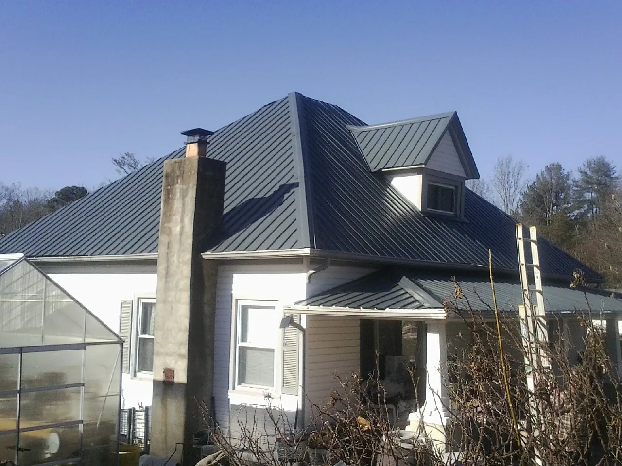 Dark blue standing seam metal roof on a white farmhouse with dormer — Slate & Tile Roof Repair by Roofing Brothers in Fox Lake