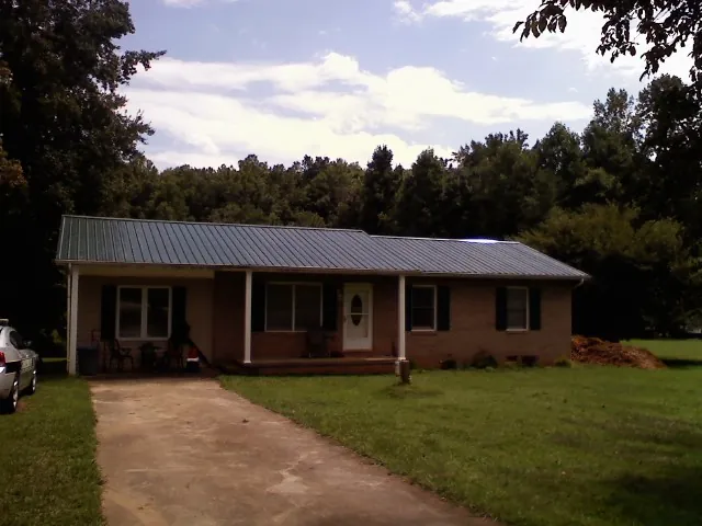 Dark green metal roof on a brick ranch with a covered porch in Fox Lake