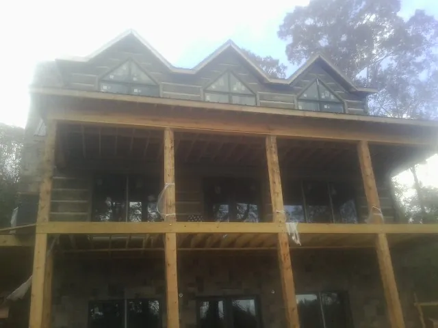 Dormers and porch framing on a large log home under construction — Roof Coating work by our crew in Fox Lake