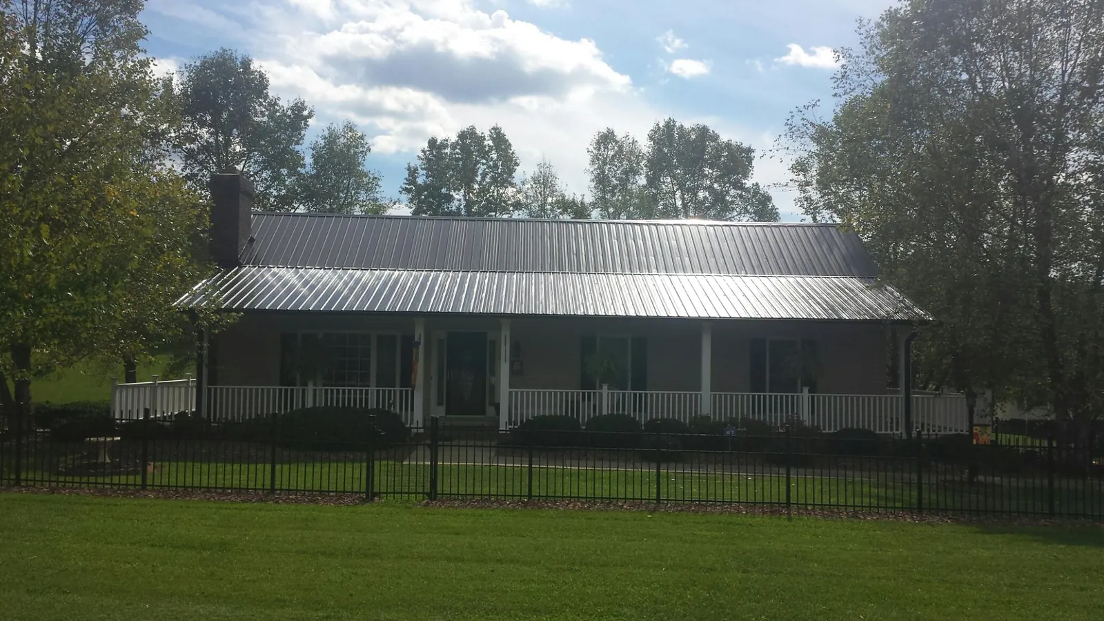Gray metal roof on a brick ranch with a full width front porch — Gutter Guard Installation work by our crew in Fox Lake